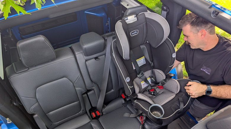 2026 Ford Bronco Badlands Review: Can This $72,000 Off-Road Icon Double as a Family Hauler? 2 A man in a black t-shirt puts a toddler seat in the back of a Ford Bronco