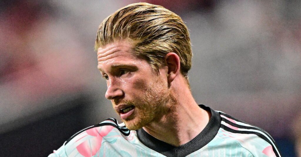 2026 World Cup: Messi Solidifies Legacy as European Stars Falter in North America 13 A photo of footballer Kevin De Bruyne looking to his right while standing on a pitch smiling and playing for the Belgium national football team in a light blue and pink shirt with a black collar and black lines running down the shoulders