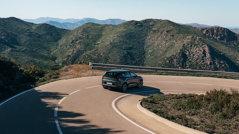 2027 Volvo EX60 First Drive: A Technical Leap Forward with Software Growing Pains 3 A dark green 2027 Volvo EX60 rounding a mountain hairpin