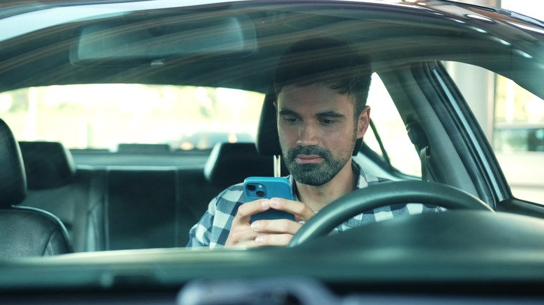 Does Charging Your Smartphone in the Car Use Fuel? Here Is the Real Impact 3 A man using his phone in a car