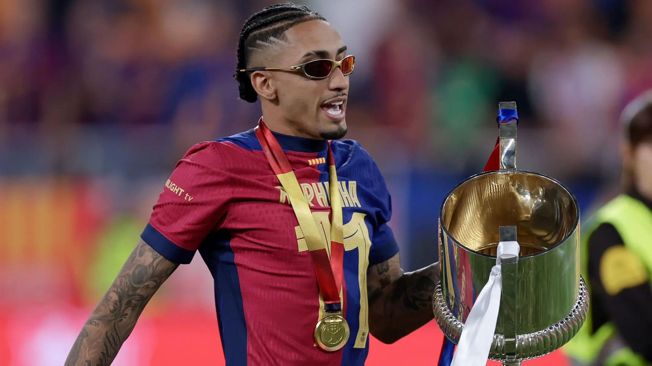 Hansi Flick Rejects Central Shift for Lamine Yamal as Barcelona Build Attack Around Right Flank Star 2 FC Barcelona winger Raphinha wearing sunglasses and a gold medal while holding a trophy
