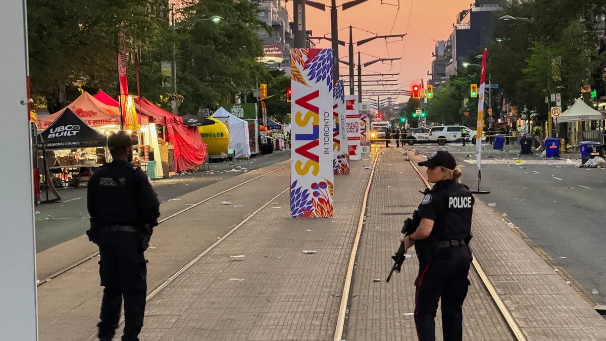 Police officers stand guard at the site of a deadly shooting at a salsa-themed street festival in Toronto, Ontario, Canada,