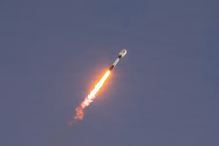 A rocket, moving upwards propelled by a plume of flame