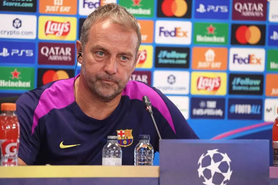 Fermín López Signals Readiness for False-Nine Role Amid Barcelona Squad Reshuffle 2 Hansi Flick wearing an FC Barcelona training shirt at a press conference with a sponsor backdrop.
