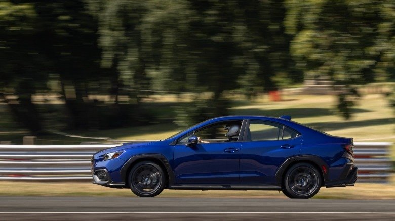 2026 Subaru WRX Base First Drive: Performance Value Purified 4 A side view of a blue WRX driving on Oulton Park past trees