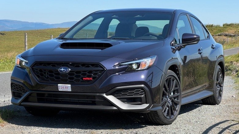 2026 Subaru WRX Base First Drive: Performance Value Purified 2 A front three-quarters shot of a Galaxy Purple Pearl WRX parked on gravel next to a road and grass on a clear day