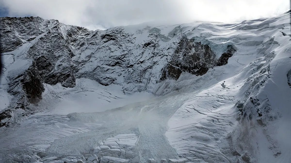 Glacial ice avalanche cascades from the Trift Glacier above a village in Saas-Grund, Switzerland.