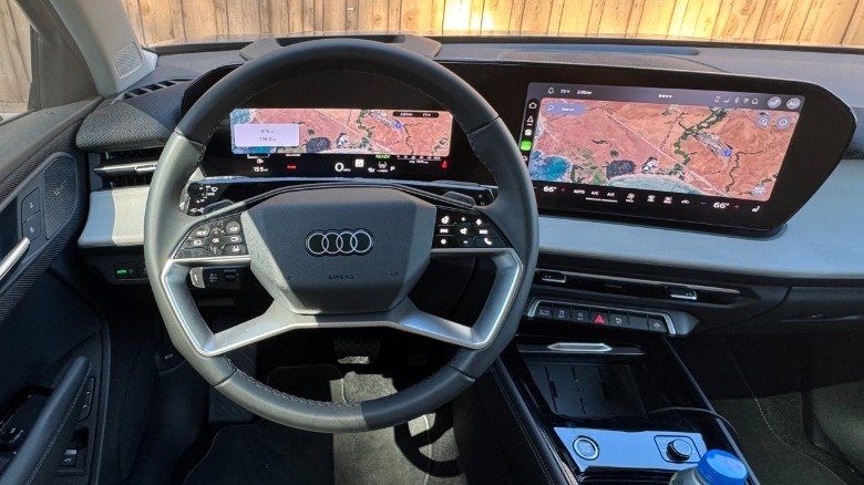 The driver's POV in the new Q3 with the map up on both the infotainment and the digital gauges with a wood fence out the windshield