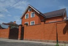 A single-family brick house behind a metal gate
