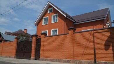 A single-family brick house behind a metal gate