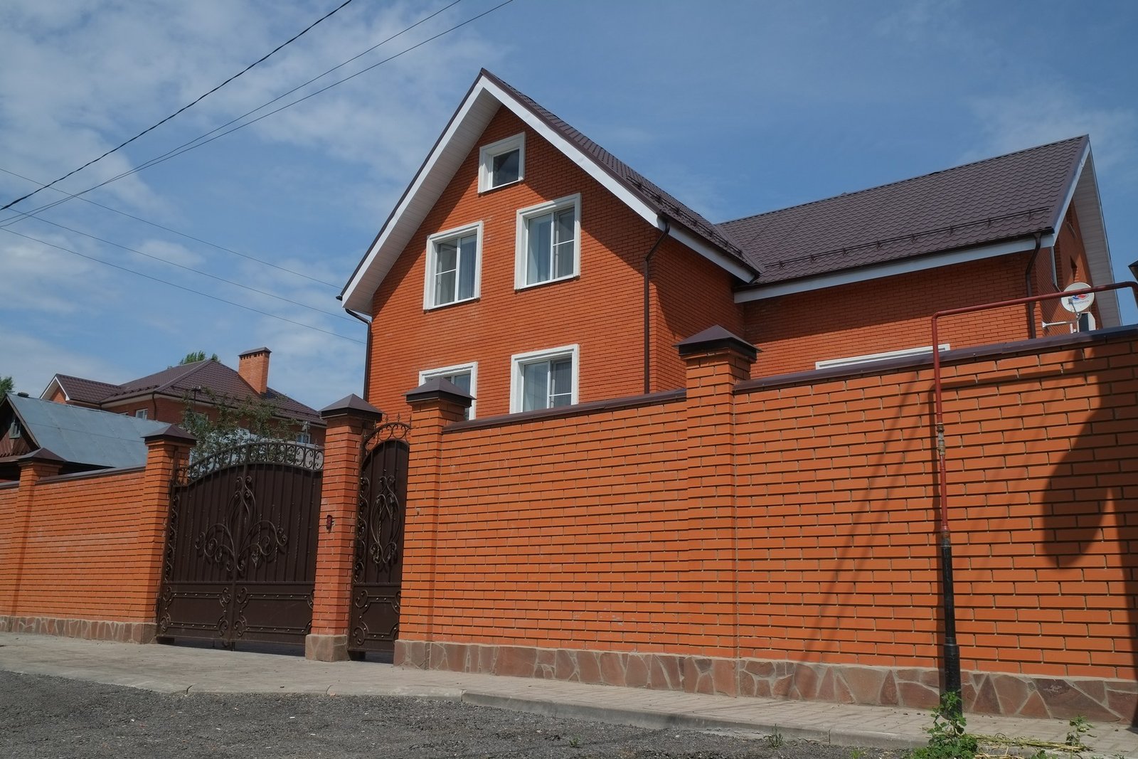A single-family brick house behind a metal gate