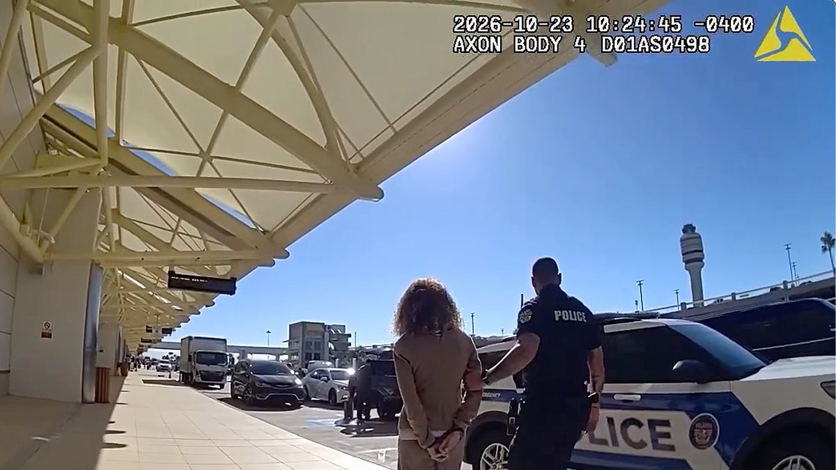 An officer escorts Irene Miller in handcuffs outside an airport