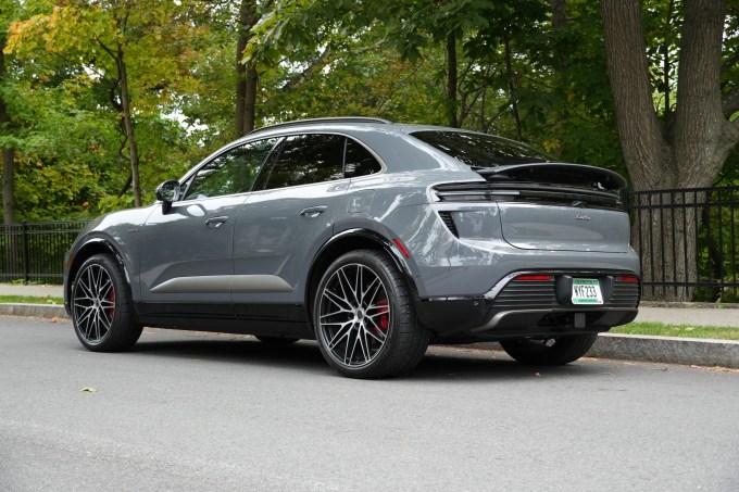 An electric Porsche Macan sits parked with its spoiler deployed.