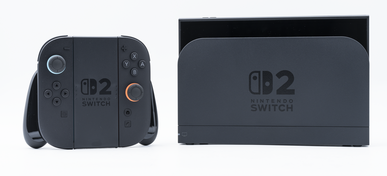 A black Nintendo Switch 2 console in its dock beside its Joy-Con 2 controllers in a grip