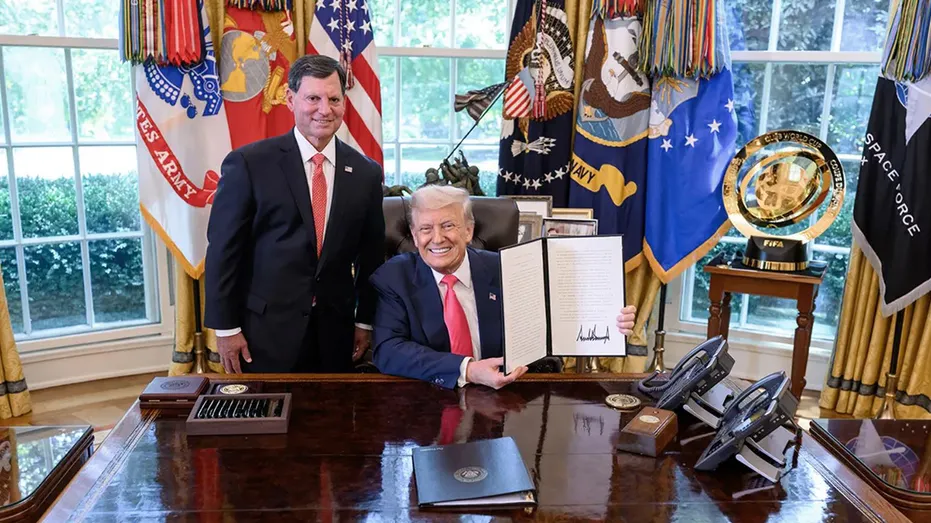 President Donald Trump holds up a signed proclamation in the Oval Office with Social Security Commissioner Frank Bisignano