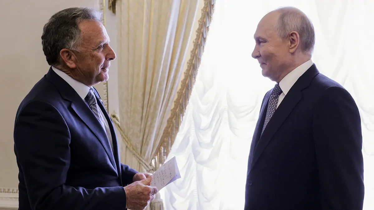 Steve Witkoff speaks to Vladimir Putin while holding a paper.